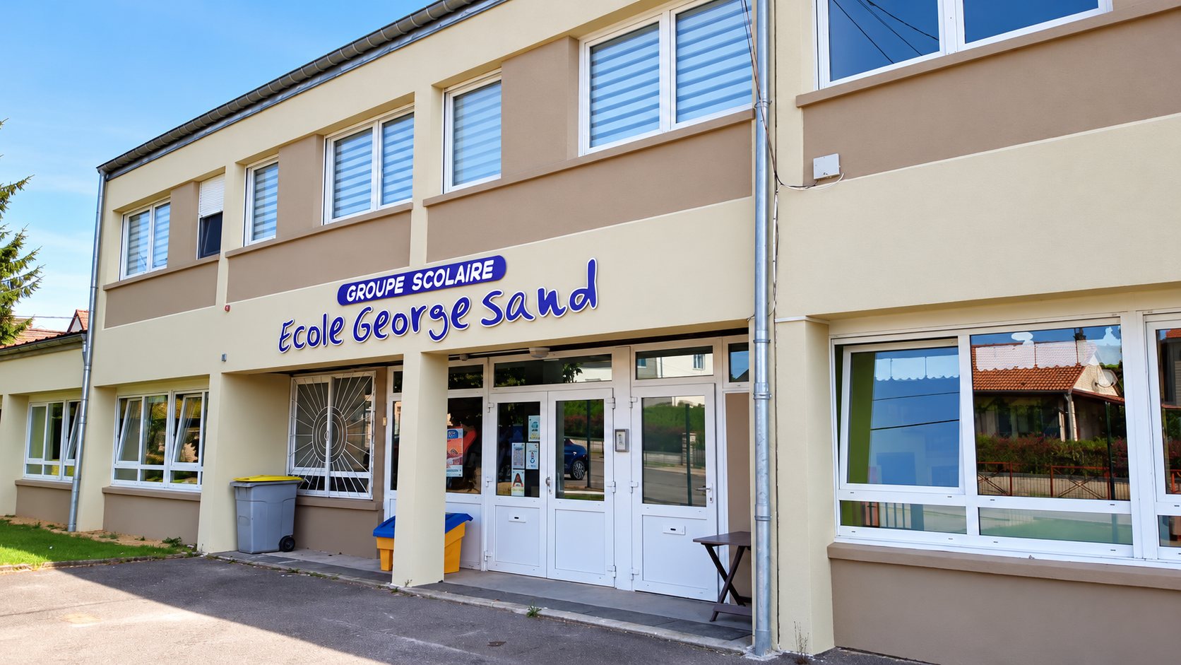 Façade beige et taupe d'un groupe scolaire avec l'enseigne « Groupe scolaire École George Sand » au-dessus de l'entrée vitrée.